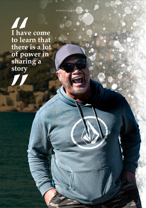 Rūpene Amato smiling while standing outside by the water, wearing a hoodie, cap and sunglasses